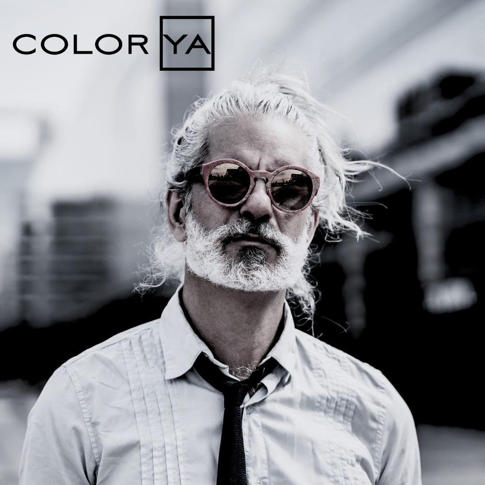 Hombre con cabello y barba blancos, gafas de sol rojas, camisa y corbata. - Luxent Professional