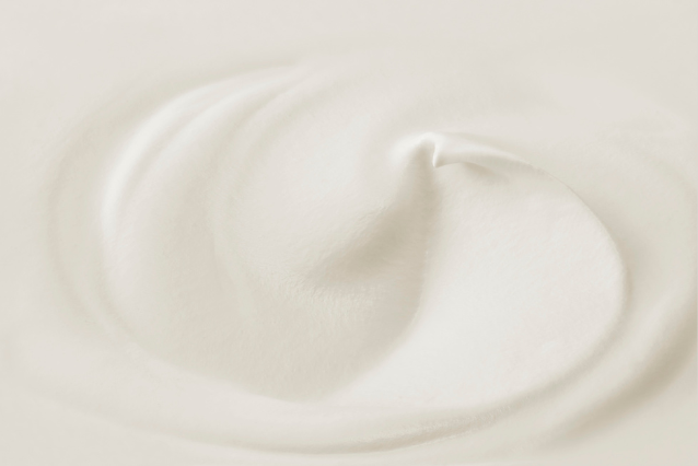 Primer plano de una rica crema blanca con suaves remolinos, perfecta para mascarillas capilares L'xent Professional.