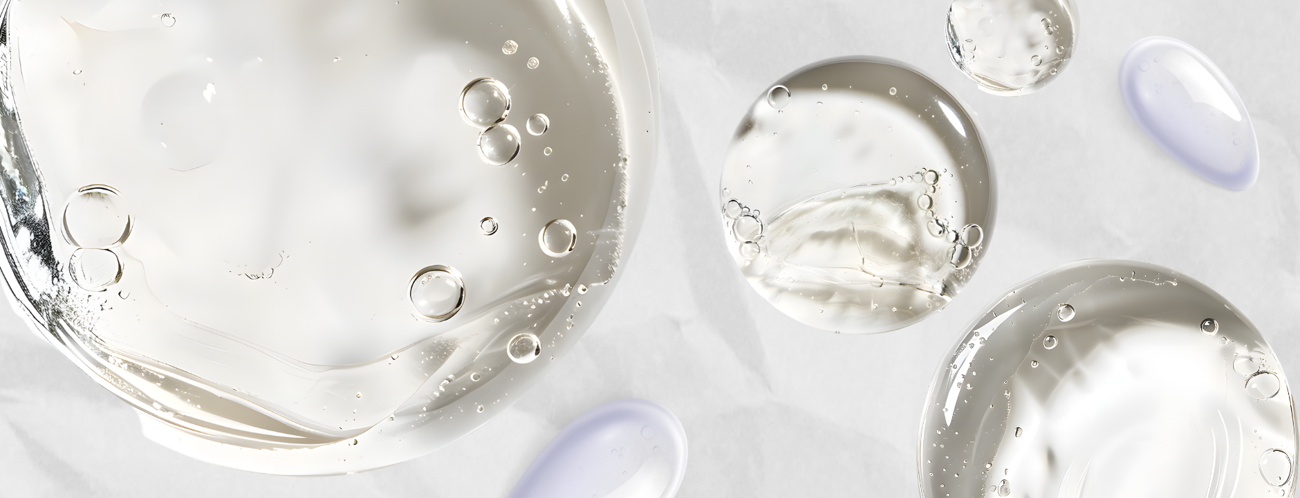 Gotas transparentes y moradas de textura líquida y viscosa con burbujas, evocando hidratación y cuidado capilar.