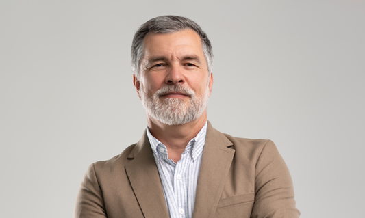 Hombre de mediana edad con cabello y barba grises, posando para L'xent Professional.
