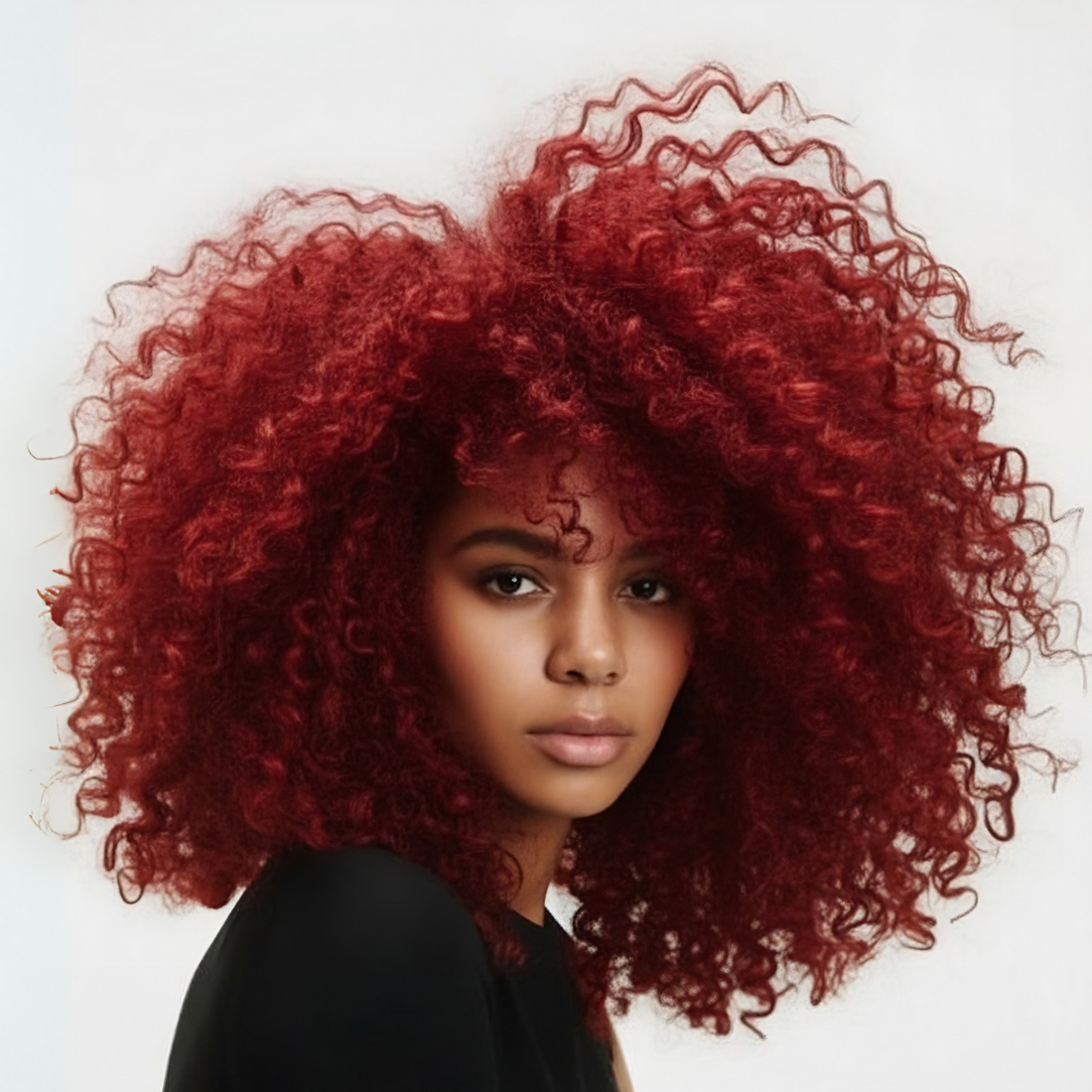 Modelo con cabello rizado rojo vibrante, mostrando un color intenso y saludable - Luxent Professional
