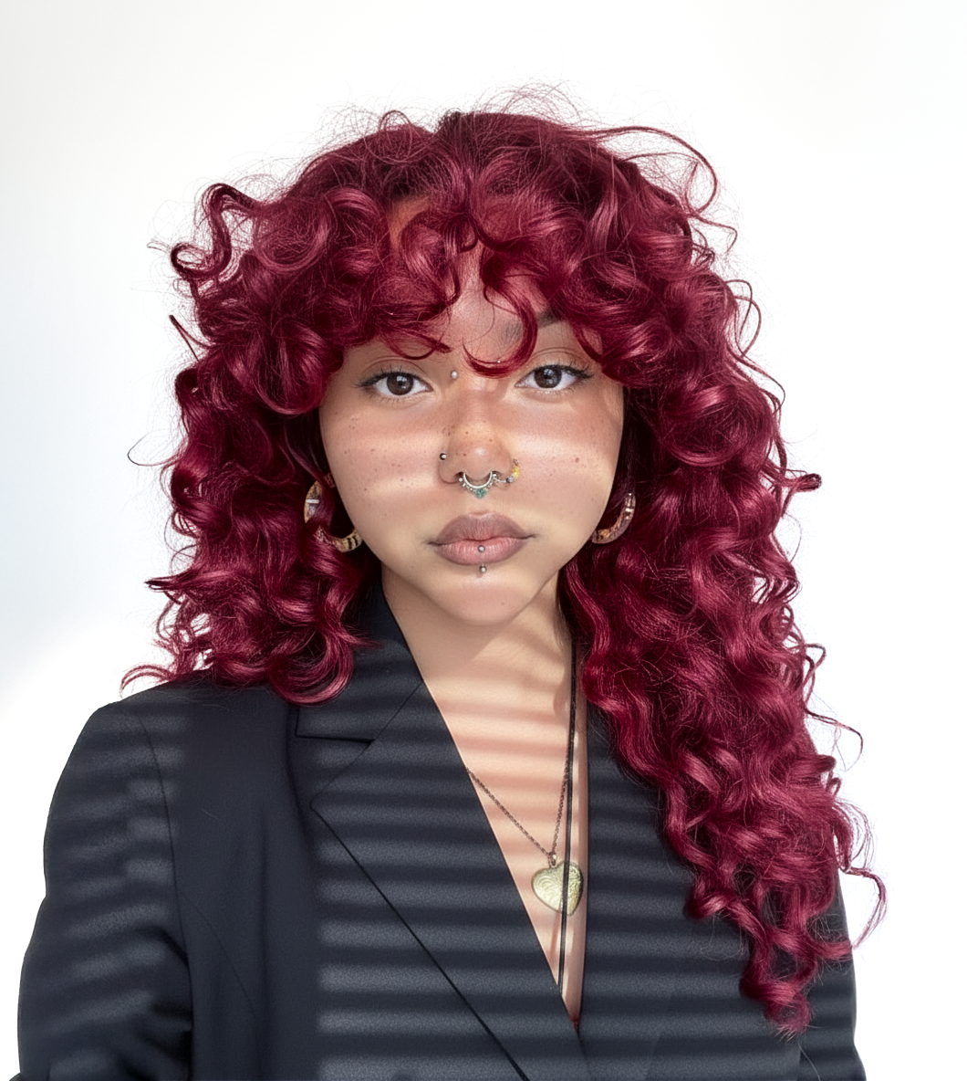 Mujer con cabello rizado rojo vibrante, mostrando un color intenso y saludable - Luxent Professional
