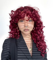 Mujer con cabello rizado rojo vibrante, mostrando un color intenso y saludable | L'xent Professional