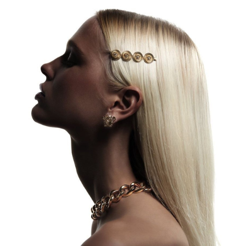 Modelo con cabello rubio platinado liso y brillante, destacando accesorios dorados en pelo y oreja.