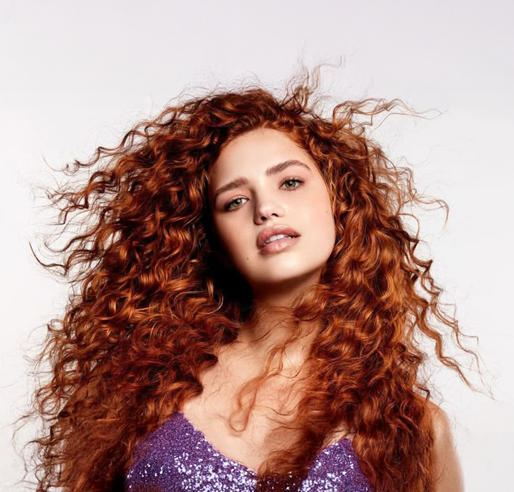 Modelo con cabello rizado rojo cobrizo vibrante y voluminoso, ideal para productos de colorac - Luxent Professional