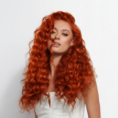 Modelo con cabello rizado rojo cobrizo vibrante, mostrando coloración profesional. - Luxent Professional
