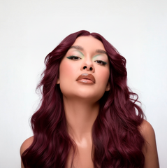 Modelo con cabello borgoña vibrante y ondulado, maquillaje de ojos verde menta. - Luxent Professional